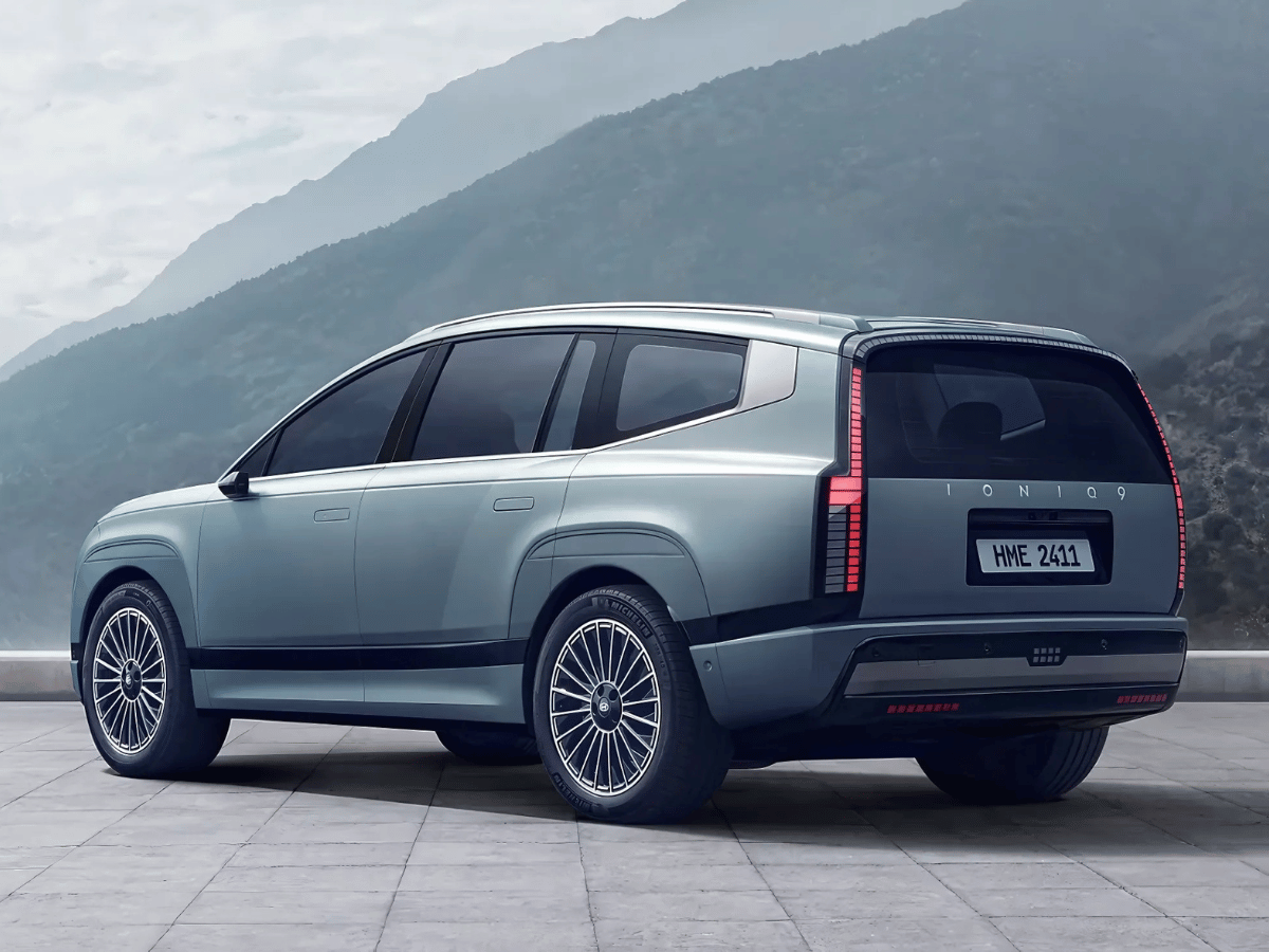 Rear-side view of a Hyundai Ioniq 9 electric SUV parked against a mountain backdrop, showcasing its futuristic design.