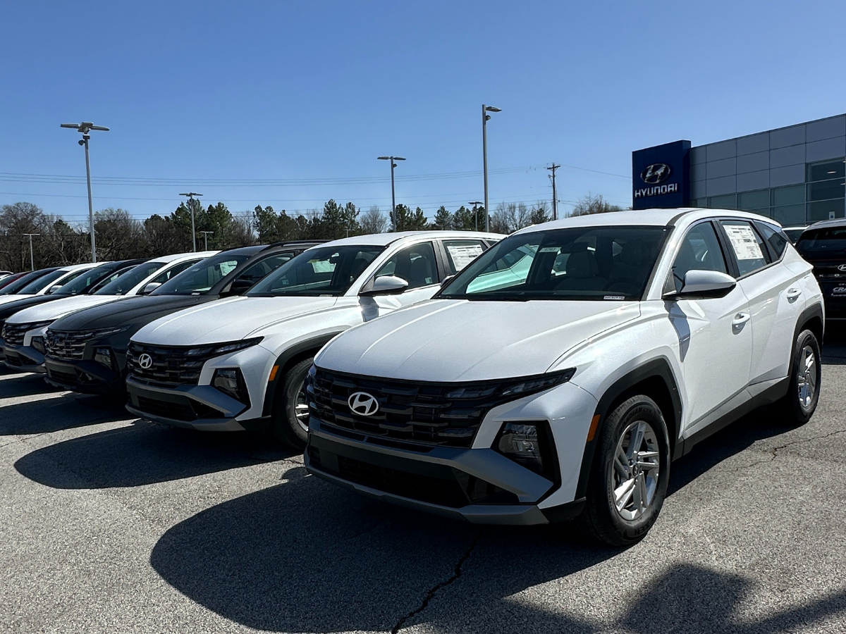 New 2024 Hyundai SUVs, including Tucson models, lined up outside Crain Hyundai of Fayetteville on a sunny day.