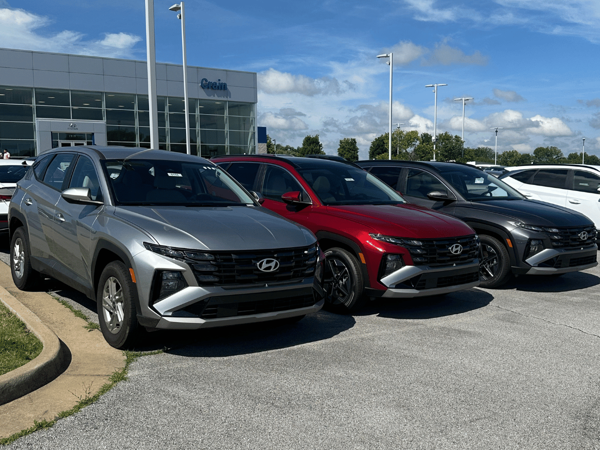 New Hyundai Tucson and Tucson Hybrid SUVs parked in front of Crain Hyundai of Fayetteville under sunny skies