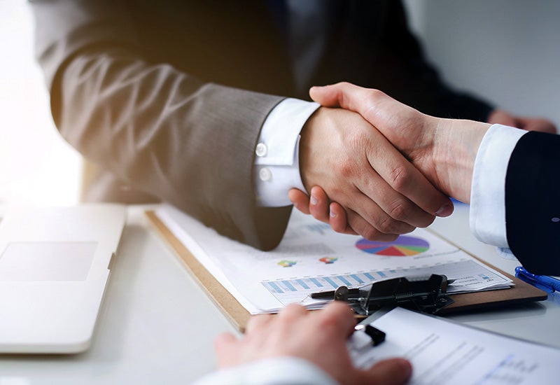 two business owners shaking hands over a car loan